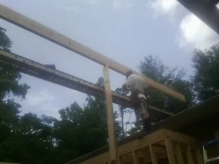 Carpenter setting a ridge beam over a new addition frame — Ice Dam Removal by Roofing Brothers in Riga