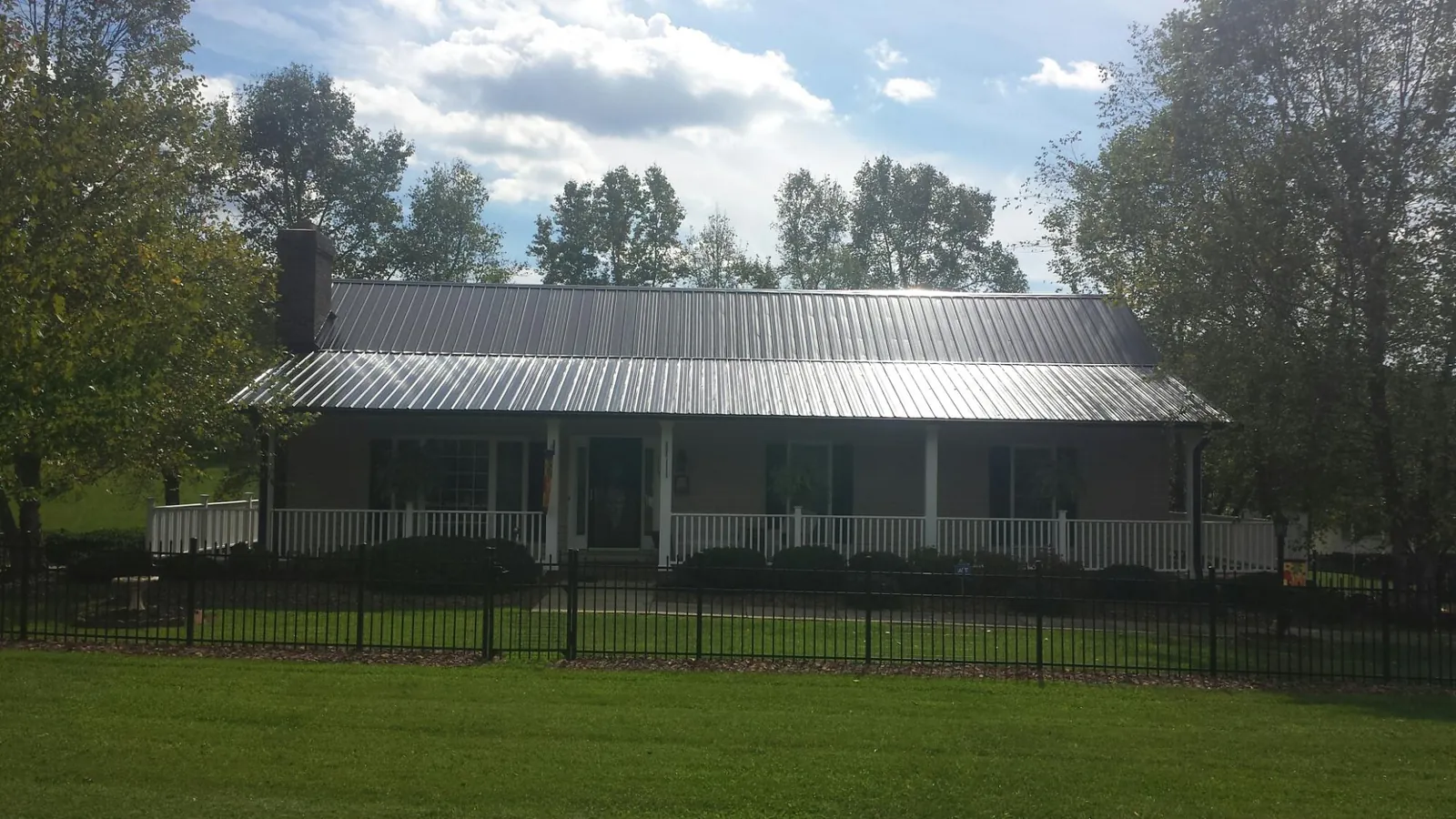 Gray metal roof on a brick ranch with a full width front porch — Gutter Guard Installation work by our crew in Riga