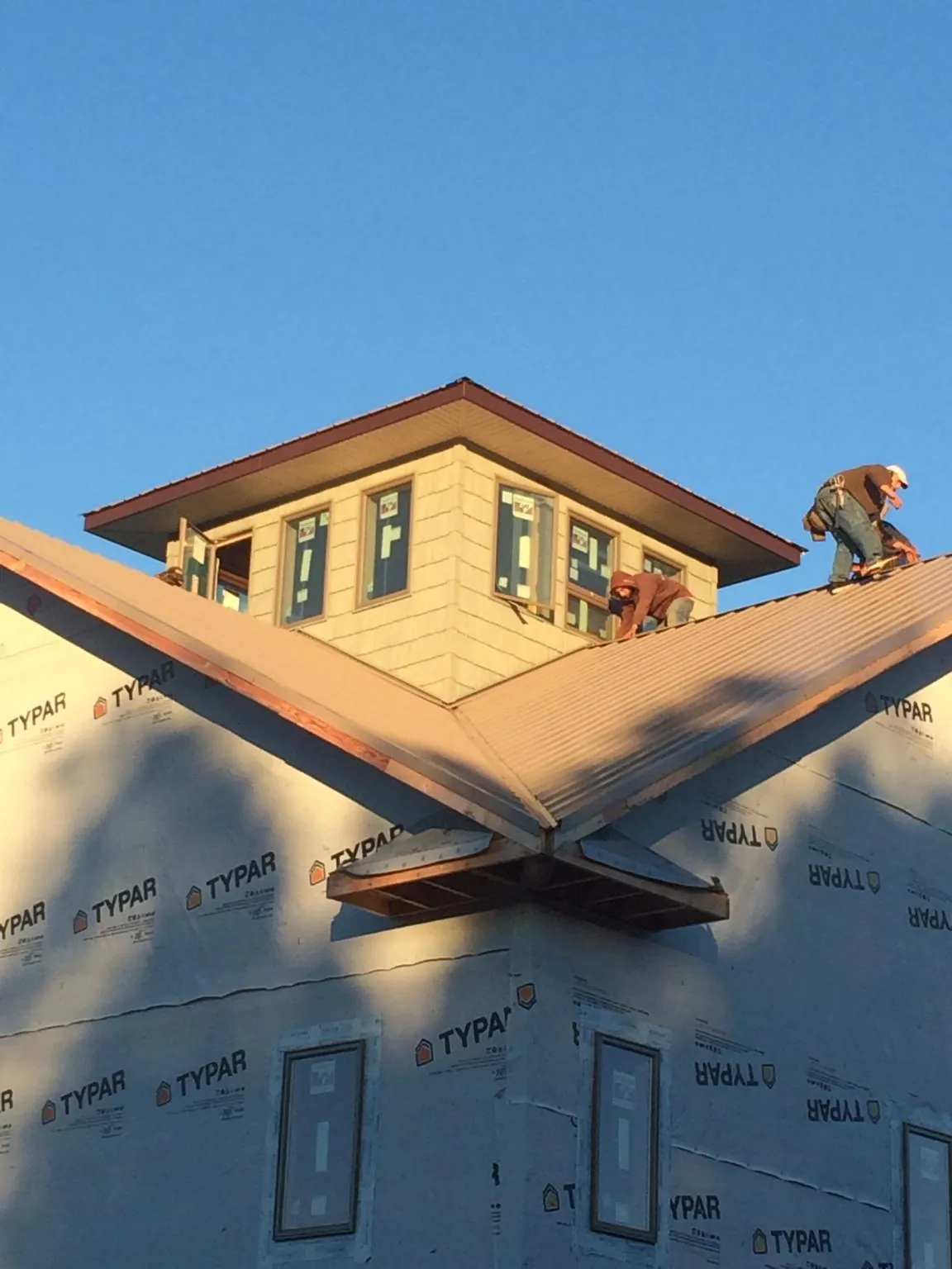 Roofers working around a rooftop cupola on a new metal roof at sunset — Roof Waterproofing in Riga by Roofing Brothers